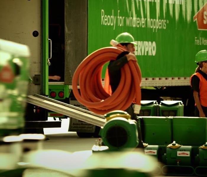 SERVPRO Employee carrying an extraction hose